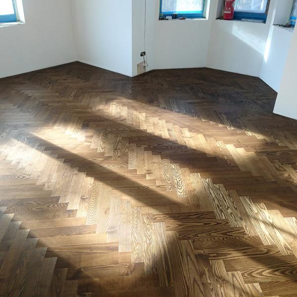 gridas parkets - skaista tonēta oša koka grīda renovētā mājā ar erkeru. Estētika un dizains: Šāda grīdas seguma izvēle dod iespēju izcelt telpas estētiku un piedāvāt izcilu dizaina risinājumu, kas atbilst jūsu interjera vēlmēm.