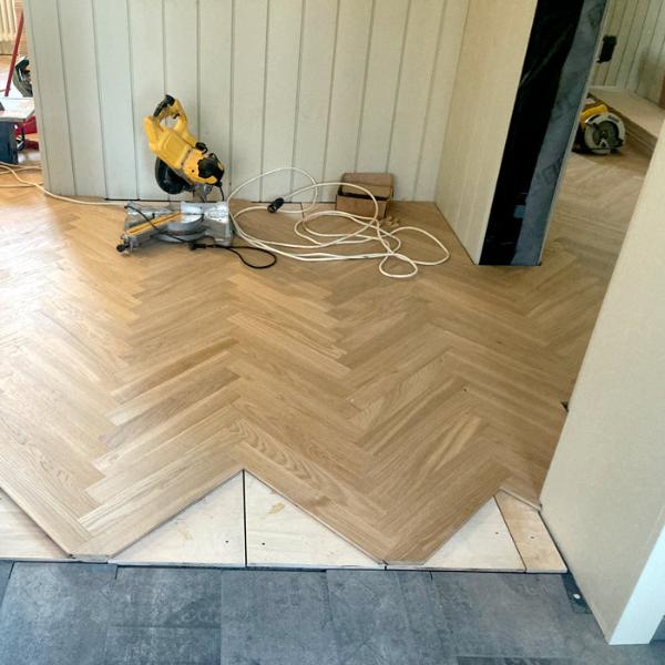 ozolkoka parketa ieklāšana klasiskās skujas rakstā, nemainot virzienu pa telpām, precīzi piezāģējoties taisni pie flīzēm, kā savienojumu izmantojot korķa līsti