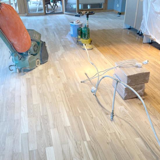 Oša parketa grīdas restaurācija tika veikta ar īpašu rūpību un precizitāti, pilnībā pāslīpējot virsmu līdz tīram koksnes slānim. Lai saglabātu oša koka dabisko, viegli pelēko toni, grīda tika piesūcināta ar bezvaska tonētu Natural eļļu, kas izceļ tās unikālo rakstu. Augstas nodilumizturības un ilgmūžības nodrošināšanai grīda tika divas reizes pārklāta ar Opal20 laku, padarot to īpaši izturīgu pret ikdienas slodzi. Meistaru rūpīgi veiktais restaurācijas darbs atjaunoja grīdas sākotnējo skaistumu un nodrošina