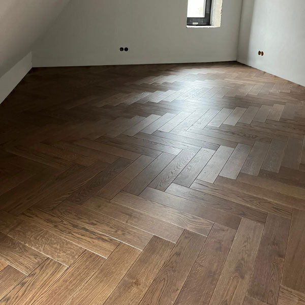 Vēsi brūnais parketa tonis English Pub ir ideāla izvēle tiem, kas vēlas tumšāku grīdas risinājumu ar izcilu kvalitāti. Divslāņu parkets (11x100x500 mm) ar strukturētu virsmu (brushed) un fāzītēm nodrošina elegantu un dabisku izskatu, kas piešķir telpai īpašu šarmu. Lai saglabātu grīdas kvalitāti, pēc ieklāšanas tā tika pārklāta ar celtniecības papīru, lai pasargātu to remonta laikā. Pēc remonta beigām grīda tiks rūpīgi attīrīta un pārklāta ar papildu vaska aizsargslāni, nodrošinot ilgmūžību un izcilu izskat