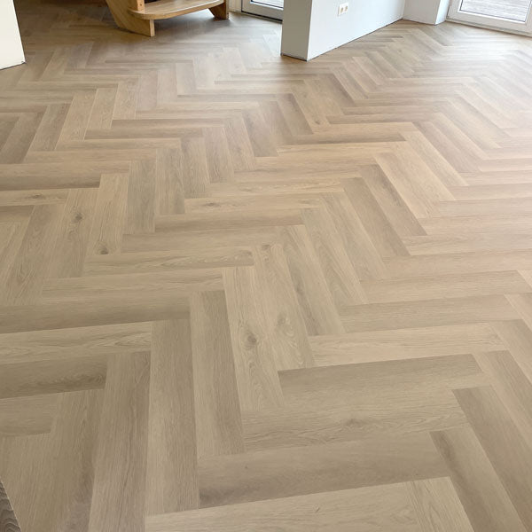 Kas ir LAXE kvarca vinila grīdas tuvplāns ar ozolkoka tekstūru un matētu herringbone rakstu. Samtaini maigas LAXE vinila grīdas detaļas ar pelēko un bēšo toņSPC kvarca vinila grīda herringbone rakstā ir eleganta un praktiska izvēle mūsdienīgam interjeram. Dabiskā ozolkoka efekta vinila grīda ar niansētu pelēko un bēšo toņu saspēli piešķir telpai harmoniju un mājīgumu. Dziļi matētais virsmas pārklājums izceļ herringbone rakstu un ir ideāli piemērots tiem, kas vēlas interjerā modernu, bet neuzbāzīgu dizainu.