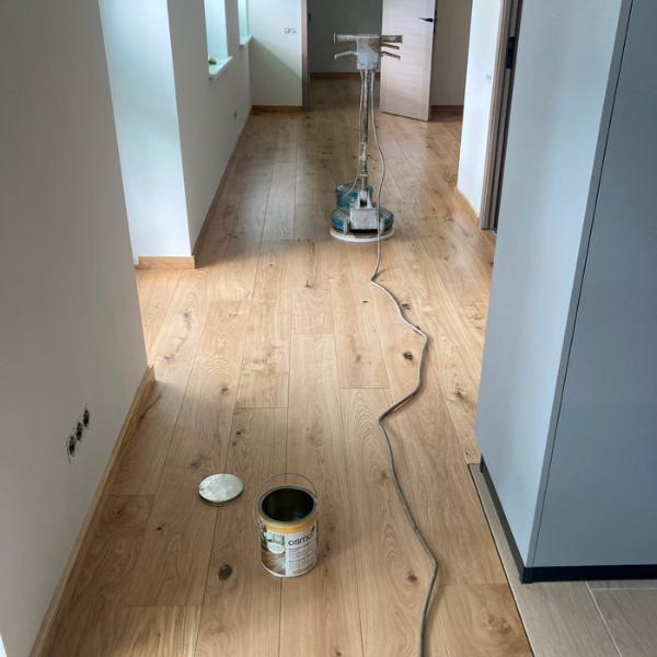 trīsslāņu dēļu ieklāšana pielīmēšana uz gruntētas dubultā grīdas reģipša, papildus uzklāta vaska kārta