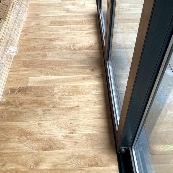 Masīvi ozolkoka dēļi (Natur / Rustic klases šķirojums), tika pielīmēti un pienagloti uz sagatavota un nostiprināta saplākšņa. Līme nodrošina stipru un ilgtspējīgu saķeri starp dēļiem un pamatni. Dēļi ieklāti taisni, pamīšus tā piešķirot telpai eleganci un plašāku vizuālu efektu.Glīta piezāģēšanās