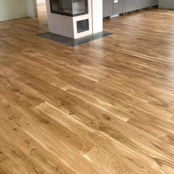 Masīvi ozolkoka dēļi (Natur / Rustic klases šķirojums), tika pielīmēti un pienagloti uz sagatavota un nostiprināta OSB. Līme nodrošina stipru un ilgtspējīgu saķeri starp dēļiem un pamatni. Dēļi ieklāti taisni, pamīšus tā piešķirot telpai eleganci un plašāku vizuālu efektu. Pēc dēļu ieklāšanas, grīda tika slīpēta un pulēta. Tam sekoja bezvaska eļļas uzklāšana ar pulējamo mašīnu. Augstākai nodiluma izturībai papildus pārklātas divas vaska kārtas ar pusmatētu eļļas cietvasku. mājīgs interjers ar kamīnu