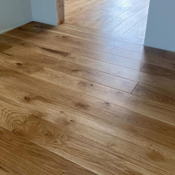 Masīvi ozolkoka dēļi (Natur / Rustic klases šķirojums), tika pielīmēti un pienagloti uz sagatavota un nostiprināta OSB. Līme nodrošina stipru un ilgtspējīgu saķeri starp dēļiem un pamatni. Dēļi ieklāti taisni, pamīšus tā piešķirot telpai eleganci un plašāku vizuālu efektu. Pēc dēļu ieklāšanas, grīda tika slīpēta un pulēta. Tam sekoja bezvaska eļļas uzklāšana ar pulējamo mašīnu. Augstākai nodiluma izturībai papildus pārklātas divas vaska kārtas ar pusmatētu eļļas cietvasku. Virziena maiņa bez sliekšņa