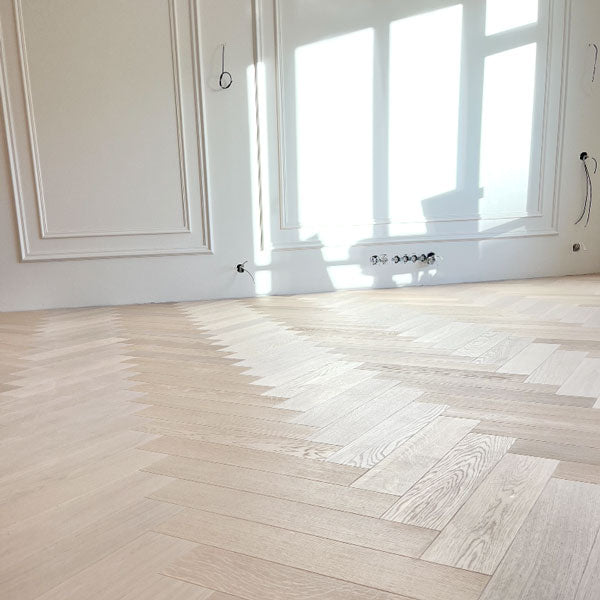 Balināts ozolkoka skujiņas parkets Cotton White ar dabisku koka tekstūru. Piemērots ieklāšanai uz apsildāmas betona estriha grīdas būvniecības projektos. Skanstes virsotnes projektu grīdas segumu pērle.